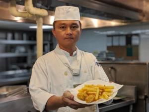 
a man in a white shirt holding a plate of food at Howard Beach Resort Kenting in Kenting
