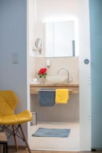 a bathroom with a sink and a yellow chair at Hotel Zum Goldenen Hirschen in Freistadt
