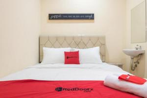 a white bed with red pillows on top of it at RedDoorz At Tebet Barat 2 in Jakarta +3 photos