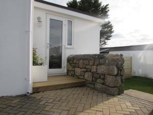 a white house with a stone wall next to a door at White Willows in Praa Sands