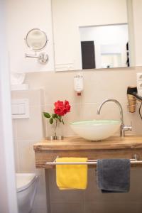 ein Badezimmer mit einem Waschbecken und einer Vase aus roten Blumen in der Unterkunft Hotel Zum Goldenen Hirschen in Freistadt