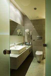 a bathroom with a toilet, sink, and mirror at Kos Aktis Art Hotel in Kos