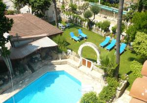 einen Blick über den Pool in einem Garten mit Liegestühlen in der Unterkunft Greenfields Country Club in Limassol