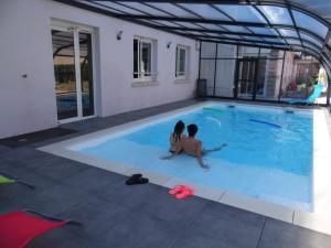 un homme et une femme assis dans une piscine dans l'établissement Chante Grelet, à Châtel-Guyon