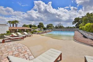 a swimming pool with lounge chairs next to a stone wall at Masseria Casina Vitale in Ceglie Messapica