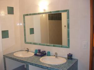 a bathroom with two sinks and a large mirror at Le Moulinage in Saint-Thomé