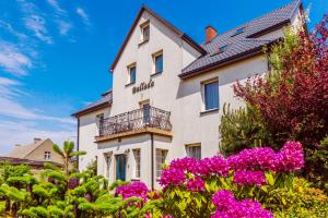 a white building with flowers in front of it at Willa Ballada in Kuźnica