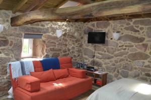 a living room with a couch and a stone wall at Penedino Mountain Cottage in Arcos de Valdevez