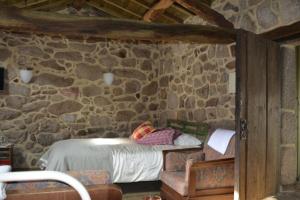 a bedroom with a bed in a stone wall at Penedino Mountain Cottage in Arcos de Valdevez