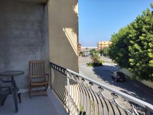 een balkon met een stoel, een tafel en een straat bij La Santera in Marina di Davoli