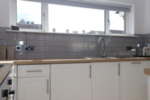 a kitchen with white cabinets and a sink at Dunfermline - Luxury 3 bedroom 2 bathroom detached house with garden in Dunfermline +31 photos