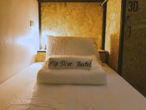 Una almohada con las palabras mosca vino hotel se sienta en una cama en Pig Dive Hostel Moalboal en Moalboal