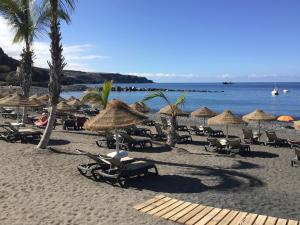 a beach with chairs and umbrellas and the ocean at Charco Las Damas in Playa de San Juan