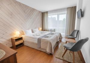 a bedroom with a bed and a chair and a window at Ośrodek wypoczynkowy Balt-Tur Feel Well Resort in Jastrzębia Góra +107 photos