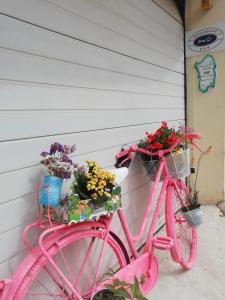 różowy rower zaparkowany obok domu z kwiatami w koszach w obiekcie Casa di Eugenia w mieście Loceri