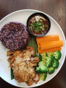 a plate of food with rice and vegetables on a table at Whereder Poshtel in Udon Thani