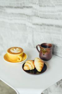 a cup of coffee and croissants on a table at Whereder Poshtel in Udon Thani
