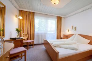 a hotel room with a bed and a desk and a window at Smaragdhotel Tauernblick in Bramberg am Wildkogel