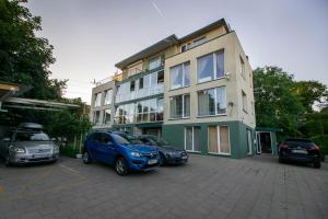 a building with three cars parked in a parking lot at Jaukūs apartamentai Free parking in Vilnius