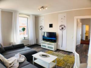 a living room with a couch and a tv at Hafencity Apartments in Tönning