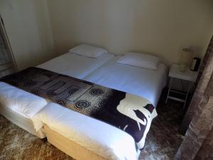 um quarto com 2 camas e lençóis brancos em Haka Hana B&B The Farm House em Port Elizabeth