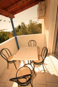 een witte tafel en stoelen op een balkon bij Holiday Tolofona Beach in Eratini