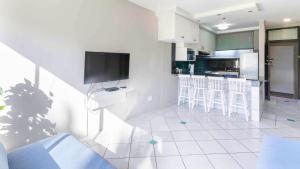 sala de estar con cocina y TV en la pared en LA Ballito, en Ballito