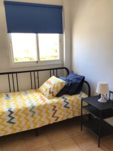 a bedroom with a bed with a blue curtain and a window at Tarajal de Playa in Playa de San Juan