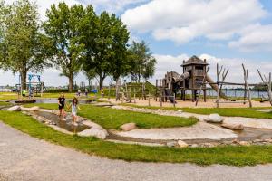 Ein Mann und ein Kind gehen durch einen Spielplatz. in der Unterkunft TopParken – Recreatiepark het Esmeer in Aalst
