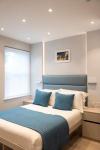 a bedroom with a large bed with blue pillows at NOX West Hampstead in London