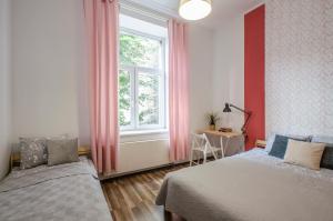 1 dormitorio con 2 camas y una ventana con cortinas rosas en OhMyHome - Kościuszki, en Łódź