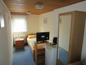 Schlafzimmer mit einem Bett und einem Schreibtisch mit einem Computer in der Unterkunft Pension Sabine in Lützen