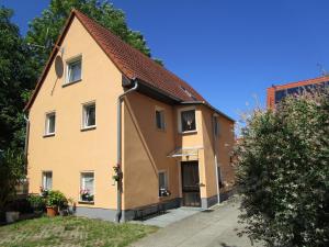 ein gelbes Haus mit rotem Dach in der Unterkunft Pension Sabine in Lützen