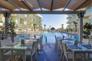 een restaurant met tafels en stoelen en een zwembad bij Dragut Point South Hotel-All Inclusive in Turgutreis