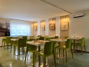 una sala da pranzo con tavoli e sedie verdi di Lucca In Villa Elisa & Gentucca a Lucca