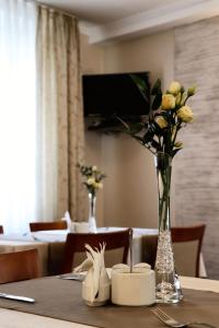 una mesa con un jarrón de flores sobre una mesa en Hotel Pod Filarami en Czeladź