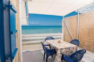 a table and chairs on a balcony with the ocean at Julie's Hermes house in Skala Kallirachis
