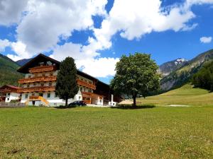 een groot gebouw met een boom in een veld bij Bergerhof in Kals am Großglockner