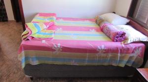 ein Bett mit einer bunten Decke und Kissen darauf in der Unterkunft Casa Linda e Arejada in São Thomé das Letras