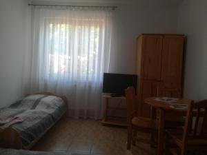 a bedroom with a bed and a table and a window at Chata Pod Różą in Lędzin