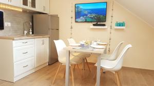 a kitchen with a table with white chairs and a refrigerator at Monika apartment Tivat in Tivat