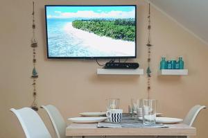 a television hanging on a wall above a table with chairs at Monika apartment Tivat in Tivat