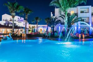 a swimming pool at night with a fountain at Yiannis Manos Hotel Resort in Malia