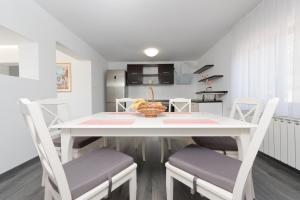een witte eettafel met stoelen en een keuken bij Castua-apartment with private heated pool in Kastav