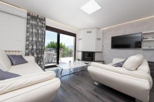 een woonkamer met twee witte banken en een tv bij Castua-apartment with private heated pool in Kastav