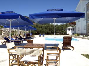 a group of chairs and tables with umbrellas next to a pool at Apartments Villa Olga in Rab