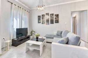 a white living room with a couch and a tv at Angel's Spirit Apartment in Zakynthos Town