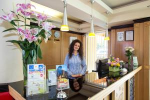 a woman standing in front of a counter with a vase of flowers at Best Western Lozenetz Hotel in Sofia