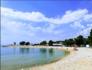 a beach with people and an umbrella in the water at App Ruzica in Crikvenica
