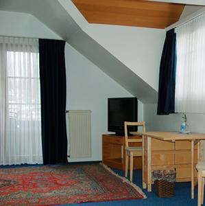a living room with a tv and a table and a desk at Hotel Gülser Weinstube in Koblenz